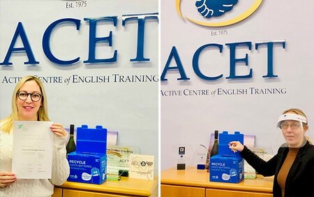Duas mulheres exibem orgulhosamente certificados em frente a uma placa com os dizeres "ACEET"."