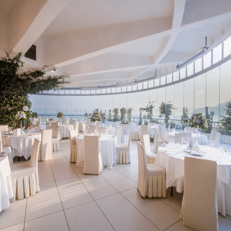 A spacious room arranged with tables and chairs, elegantly set up for a wedding celebration.